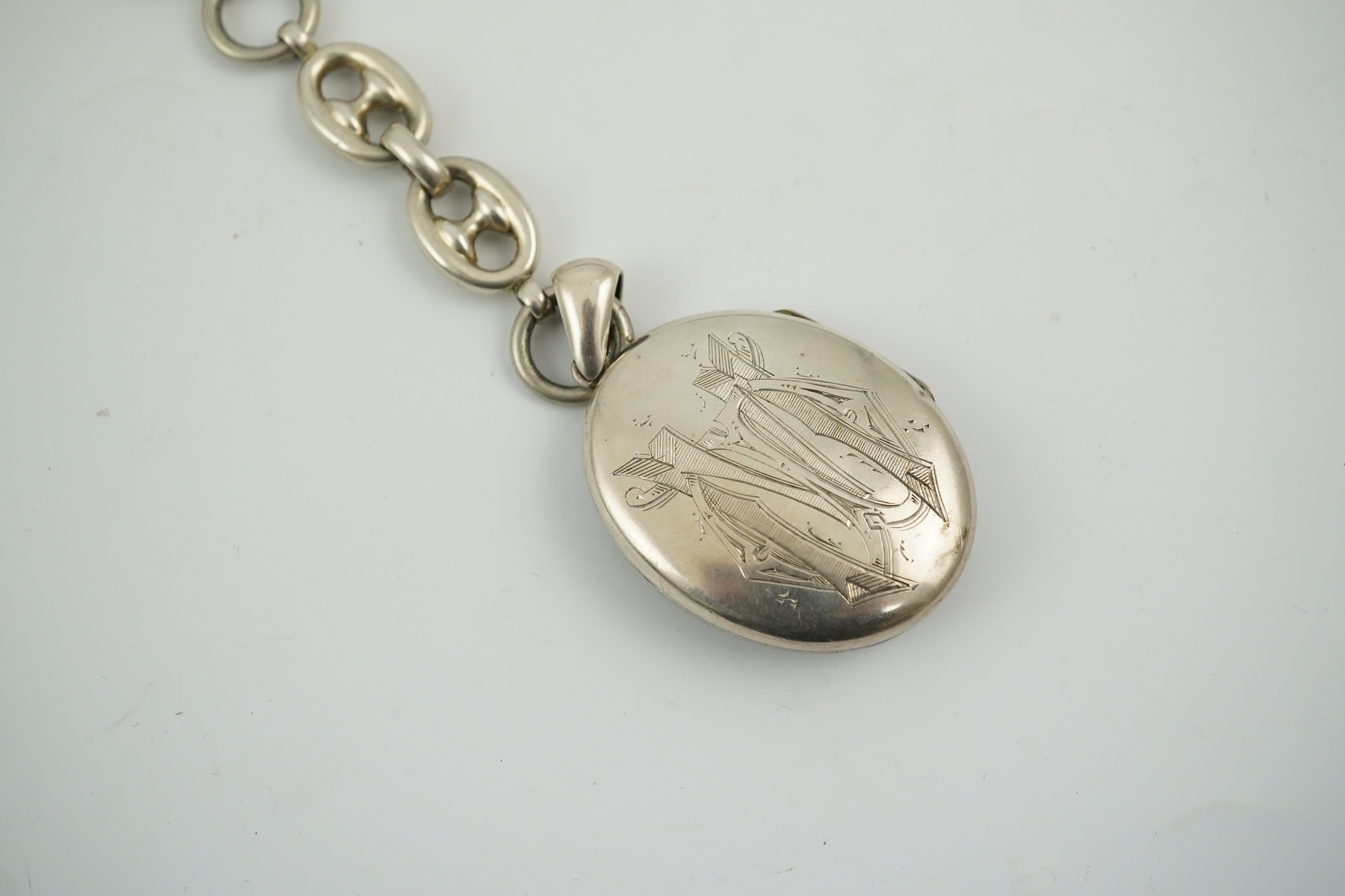 A late Victorian white metal oval locket with Japonaiserie decoration, 47mm, on a white metal chain. Condition - fair to good